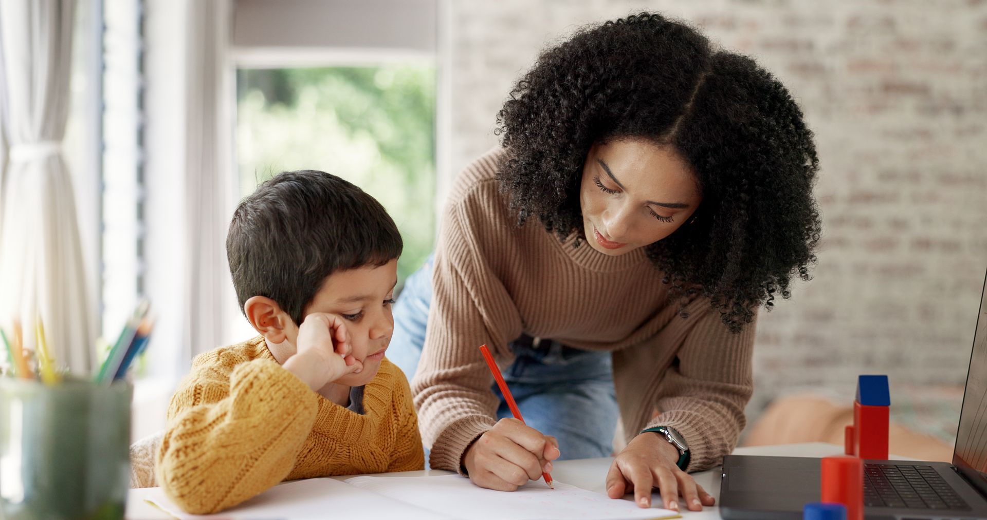 A woman is helping a young boy with his homework.