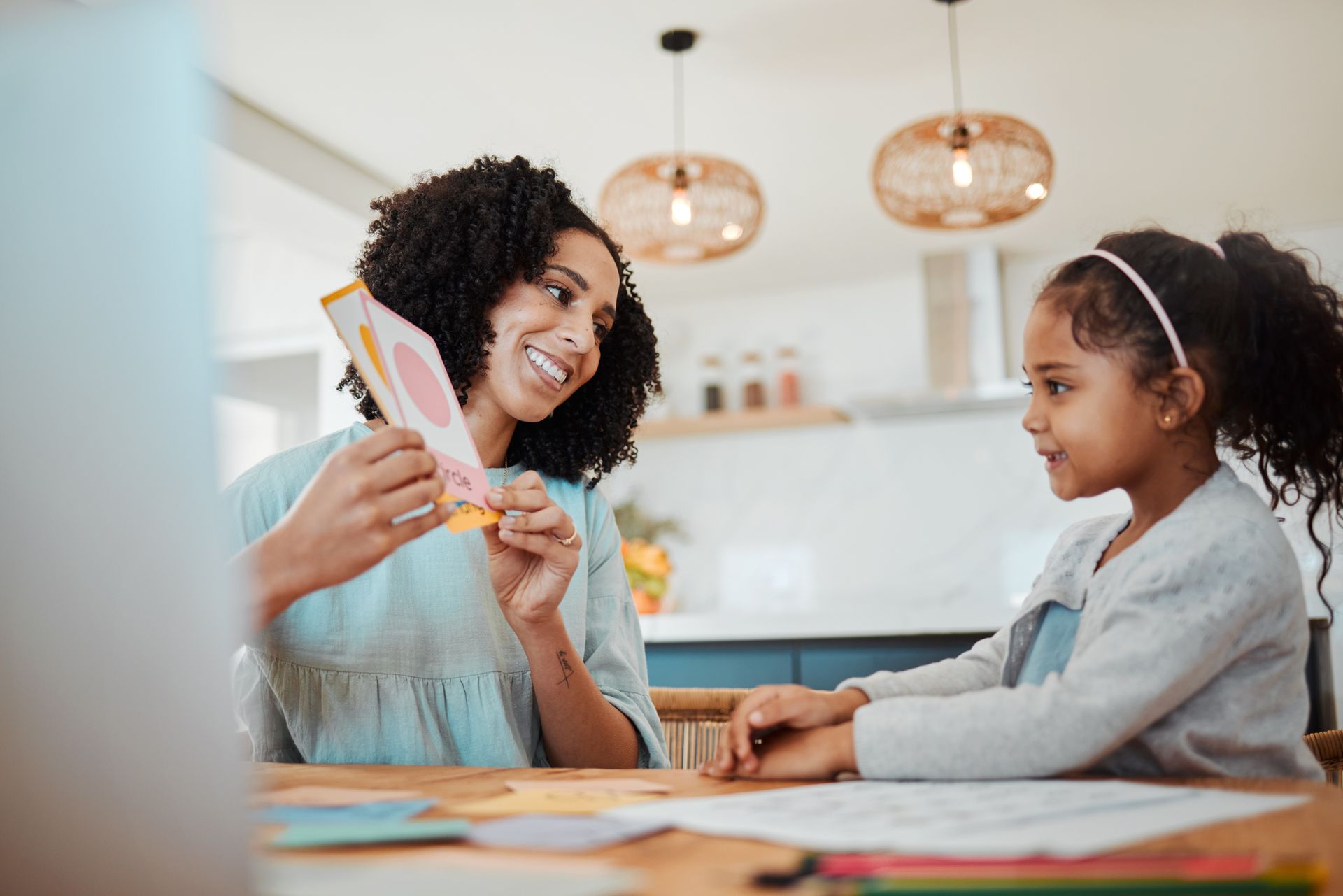 A woman and a little girl are sitting at a table making cards.