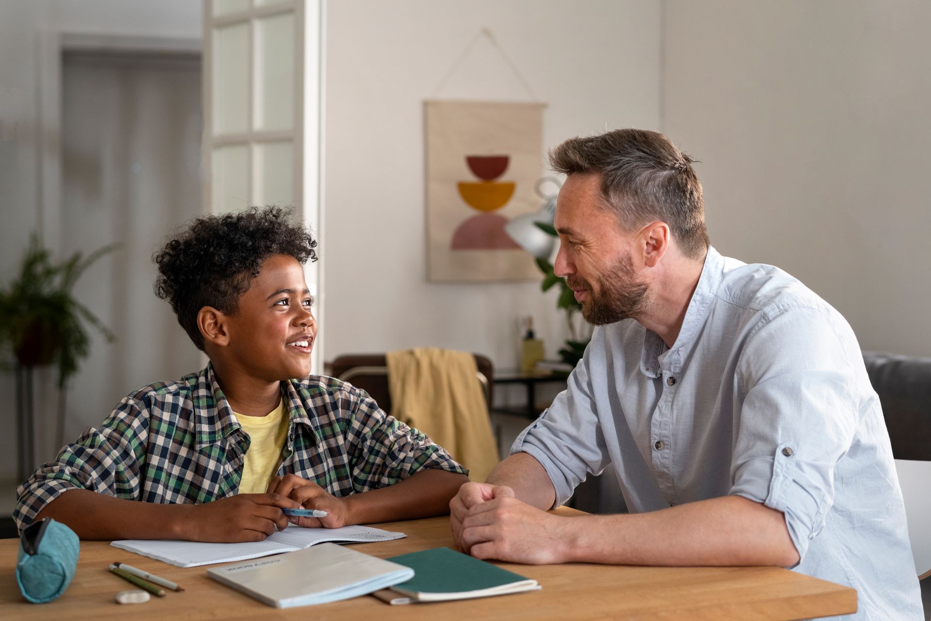 A man and a boy are sitting at a table talking to each other.