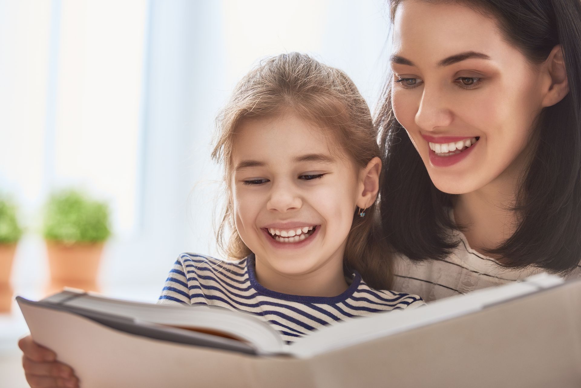 A woman and a little girl are reading a book together.