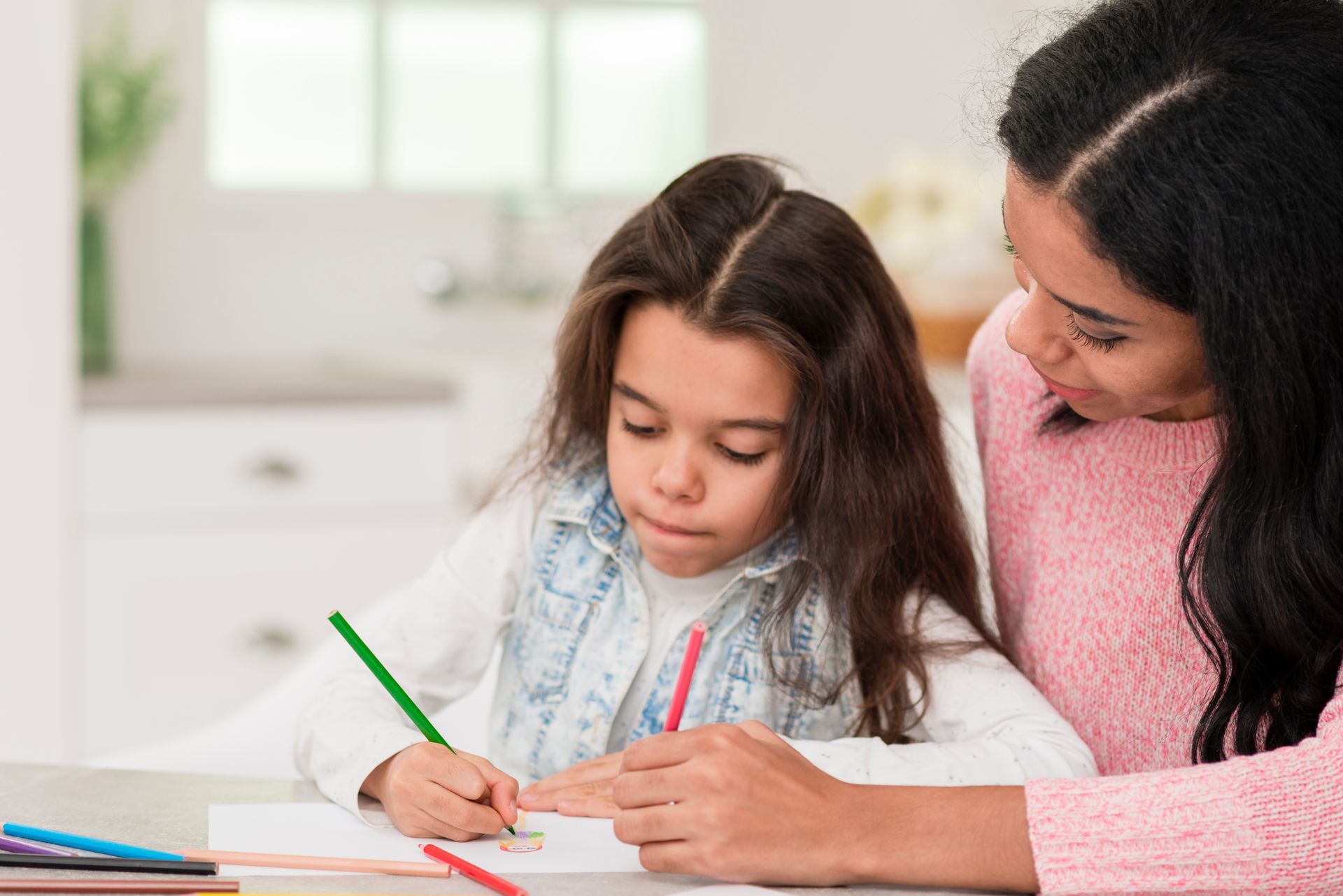 A woman is helping a little girl with her homework.