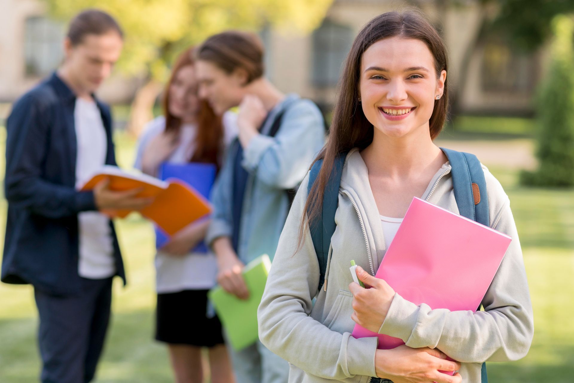 A woman is holding a pink folder in front of a group of students.