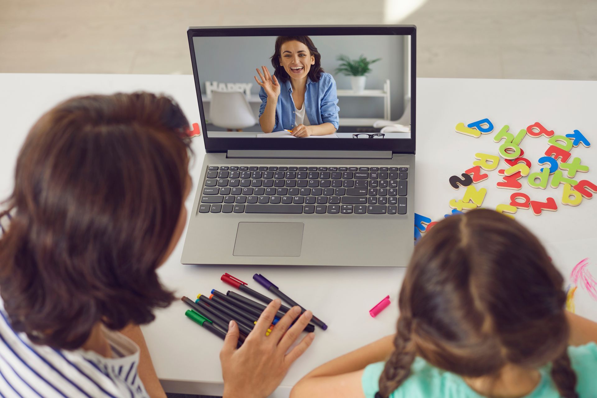 A woman and a child are sitting at a table using a laptop computer.