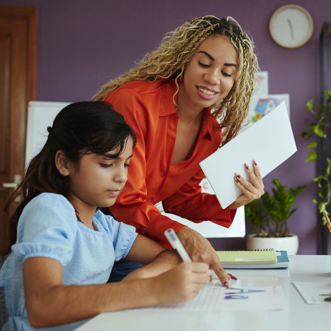 A woman is helping a young girl with her homework