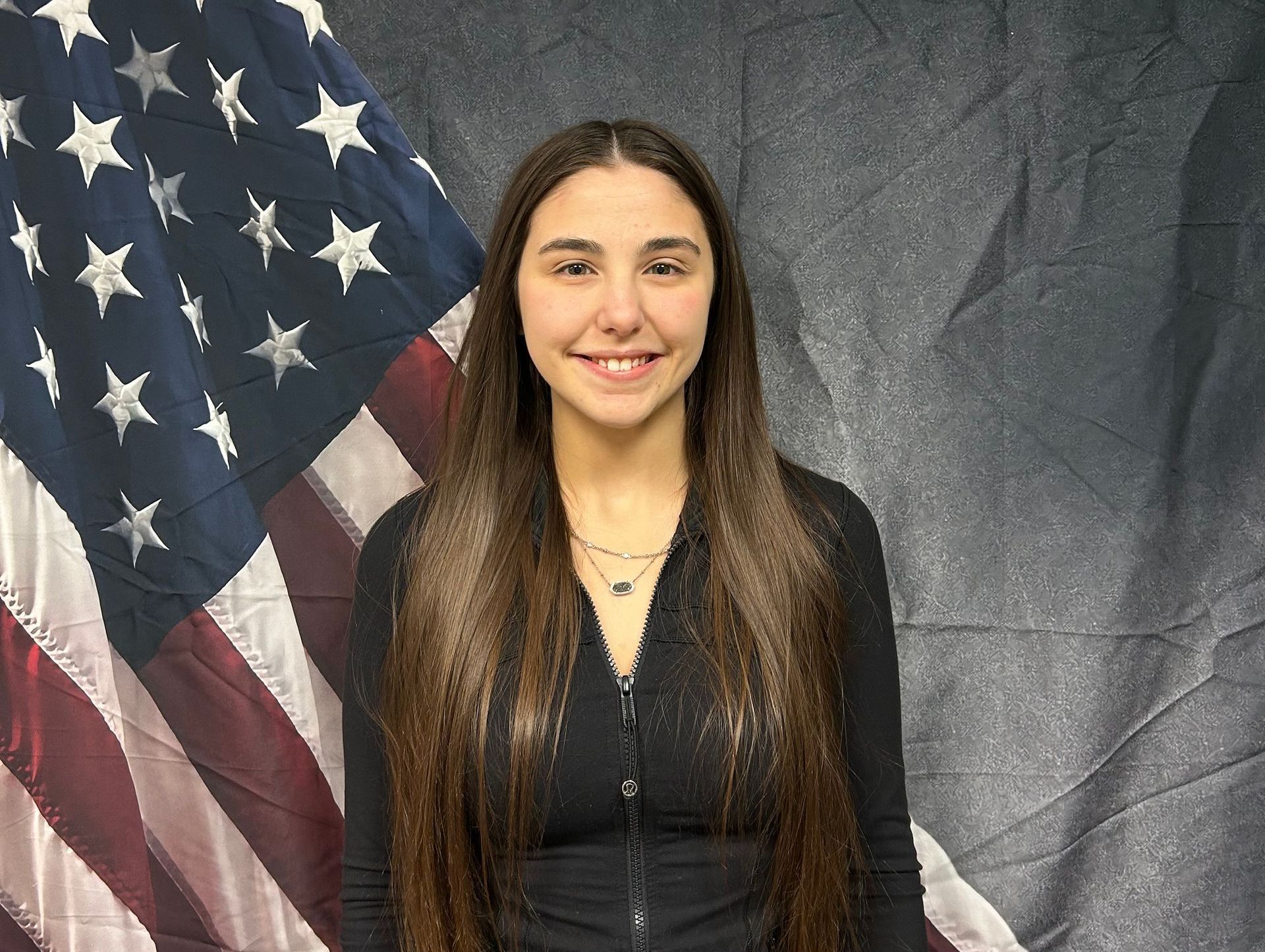 A woman is standing in front of an american flag.
