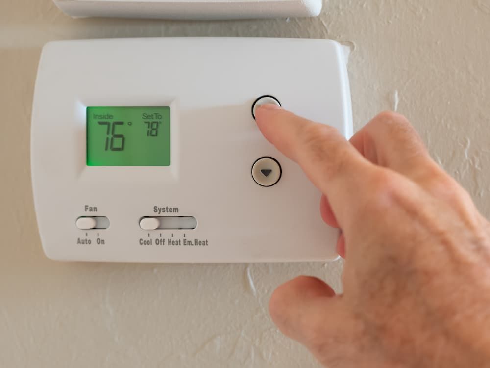 a close up shot of a thermostat and a person turning it up