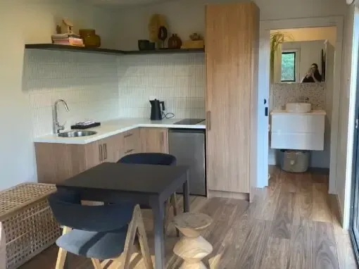 Small kitchen with dining area, light wood cabinets, and a bathroom in the background.