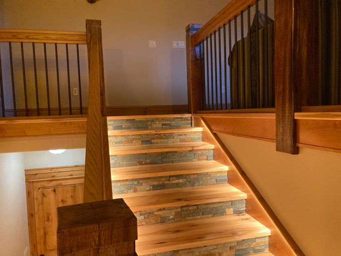 A wooden staircase with stone steps and a metal railing