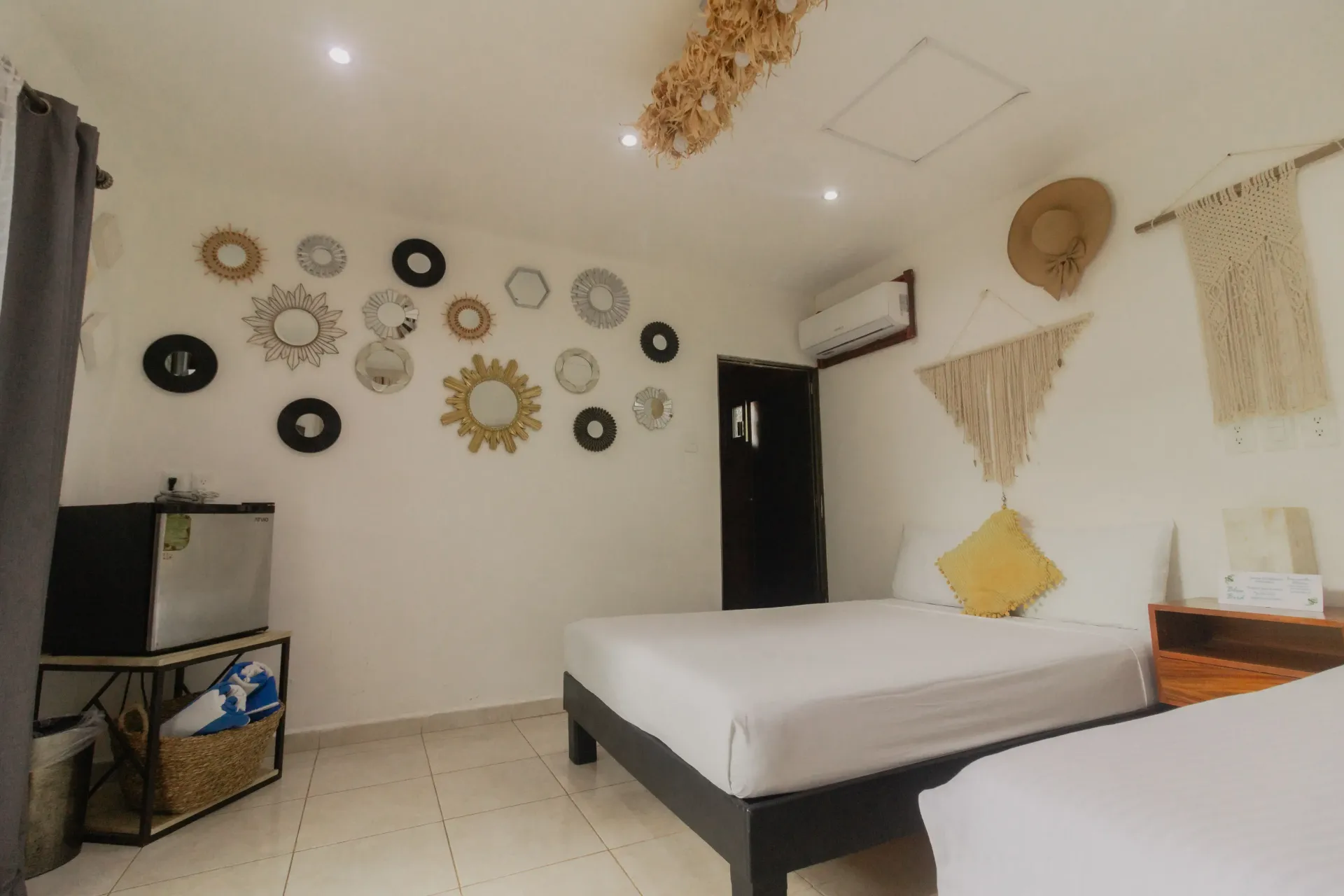 Habitación pequeña con dos camas, decoración en las paredes, un mueble para la televisión y tapices tejidos en las paredes.
