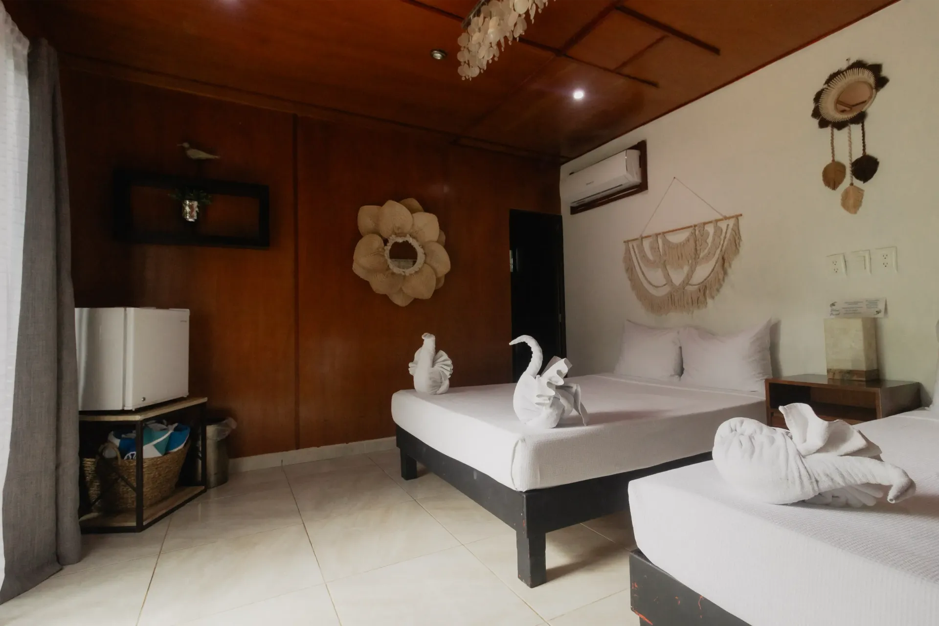 Habitación rústica con paredes revestidas de madera, dos camas individuales y sábanas blancas con iluminación cálida.