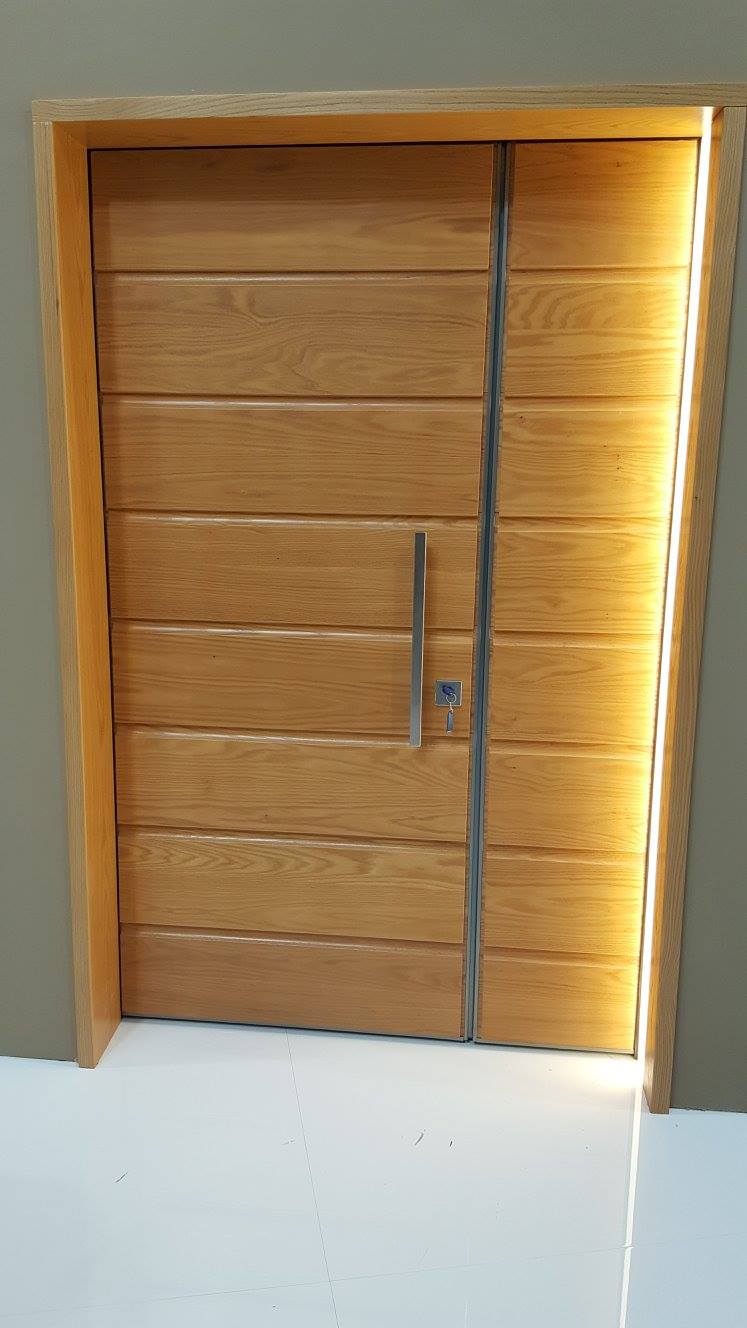 Porta in legno con assi orizzontali, maniglia argentata, inserita in una cornice di colore chiaro.