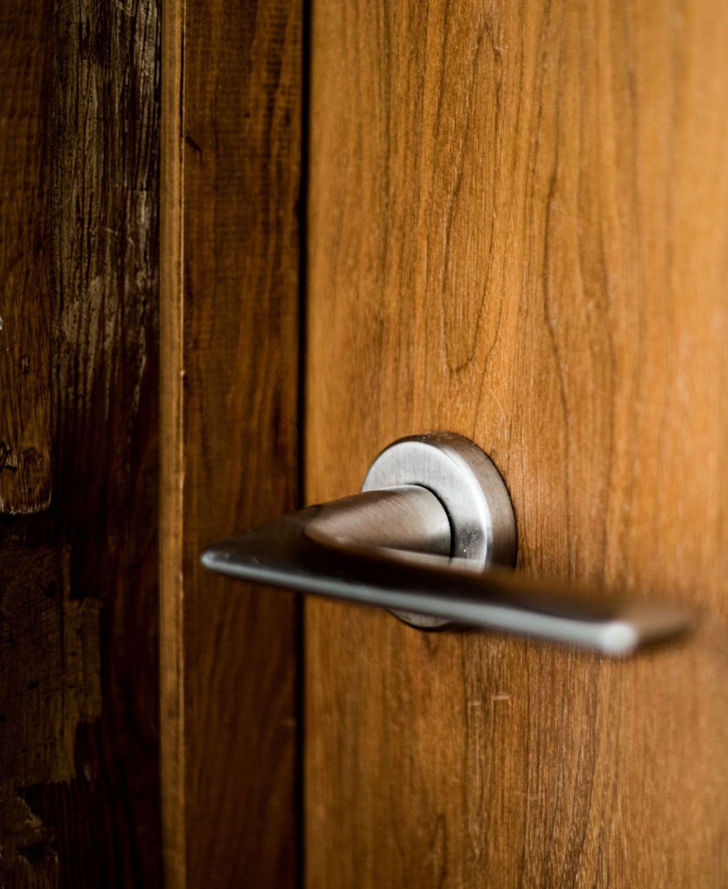 Maniglia argentata su una porta di legno, primo piano.
