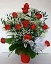 Red roses in a red vase, white baby's breath, and a silver bow.