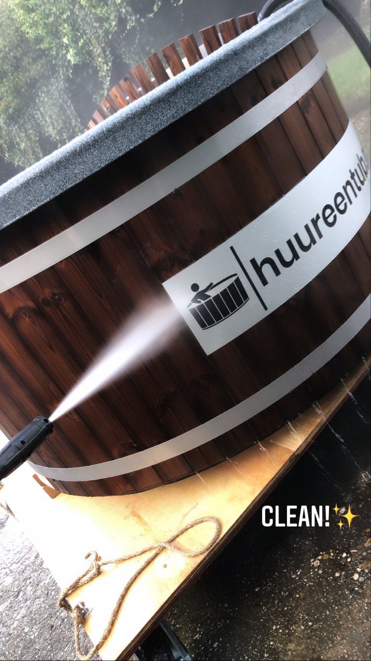 Een houten hottub met logo wordt schoongemaakt met een hogedrukreiniger.