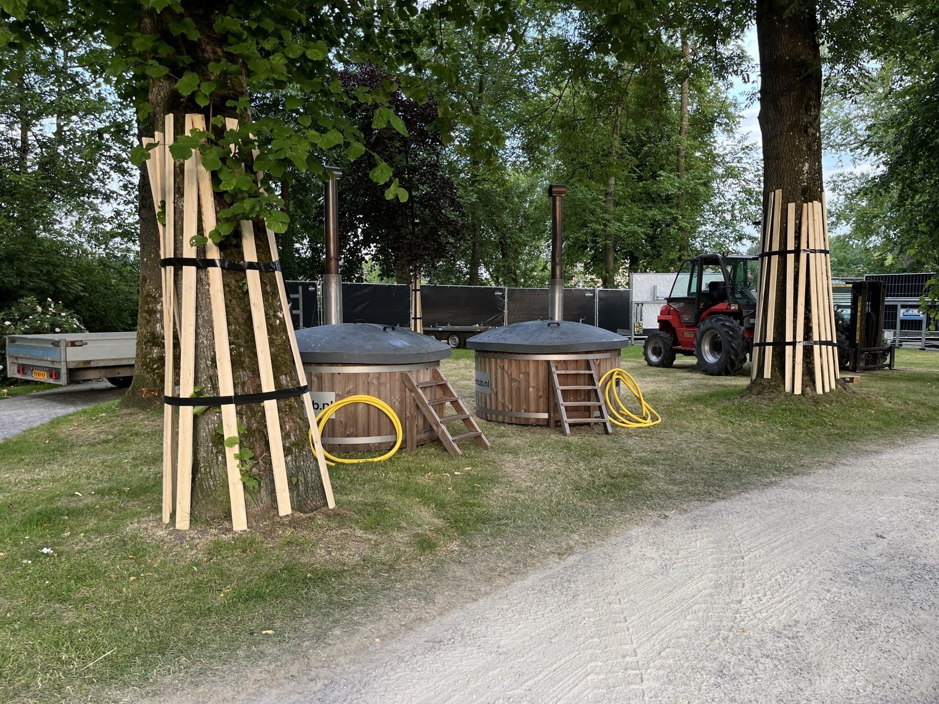 Twee houten hot tubs staan tussen de bomen.