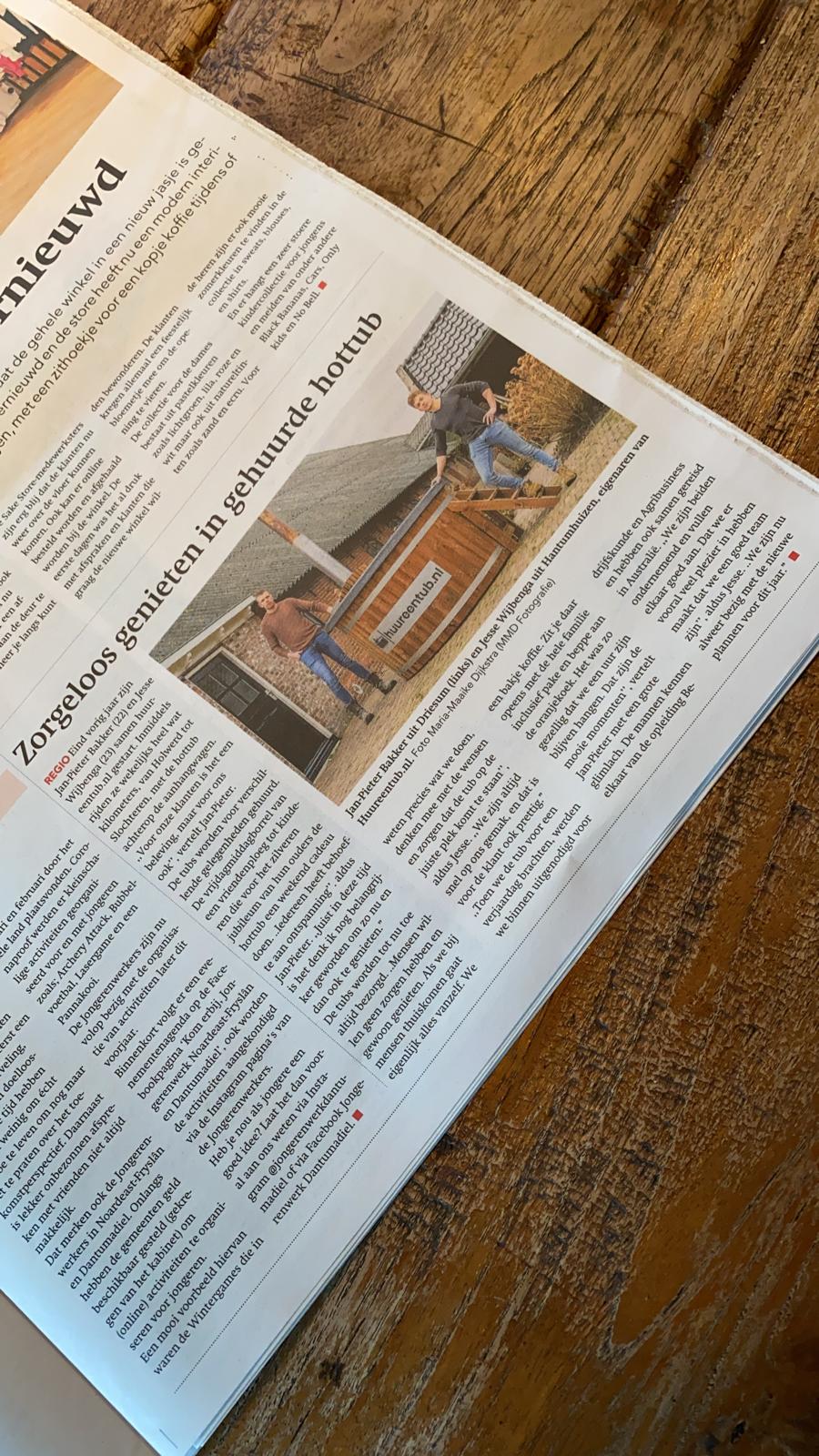 Er ligt een krant met artikel over een hottub op een houten tafel.