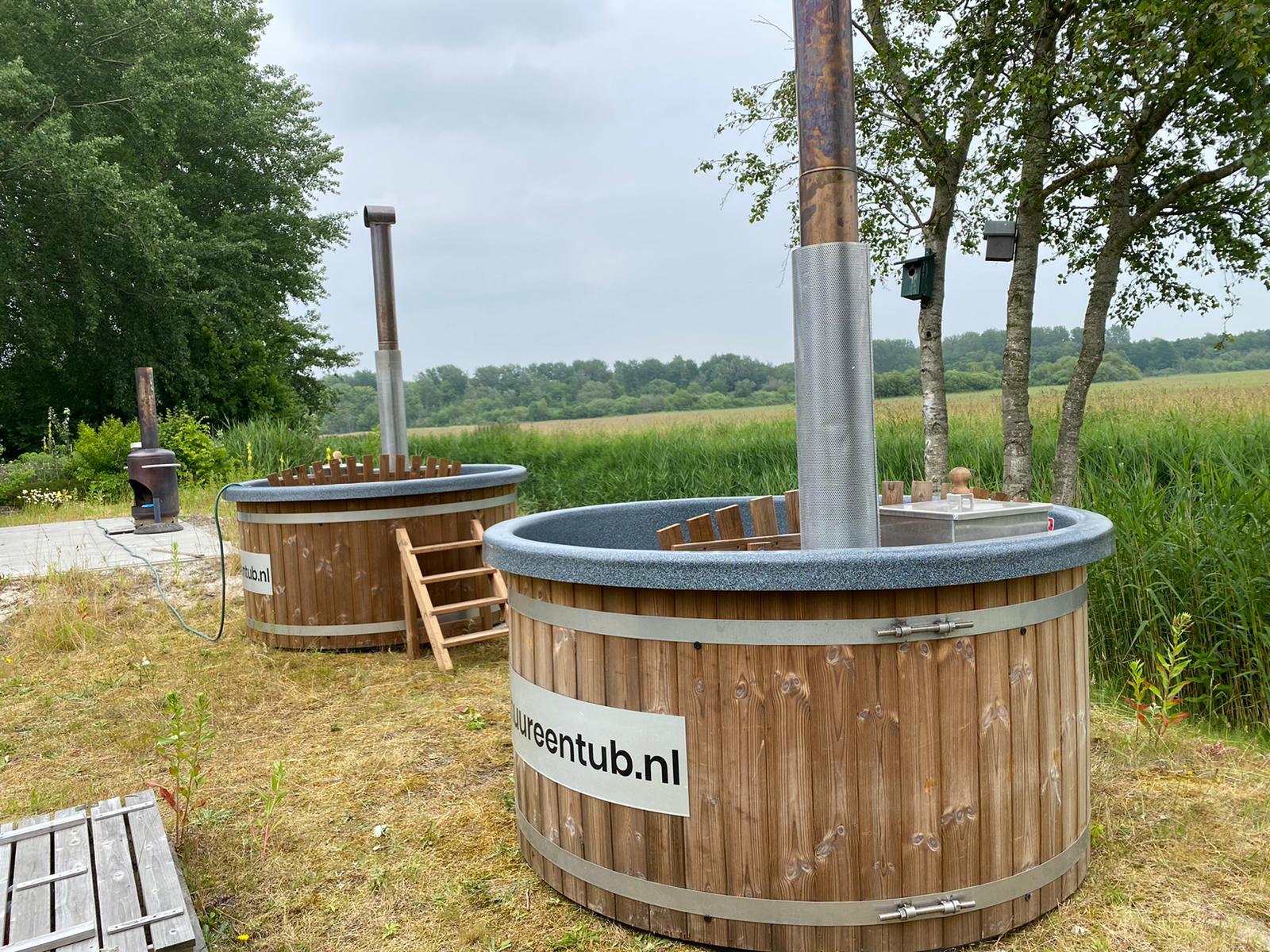 Twee houten hottubs staan op een met gras bedekt veld.