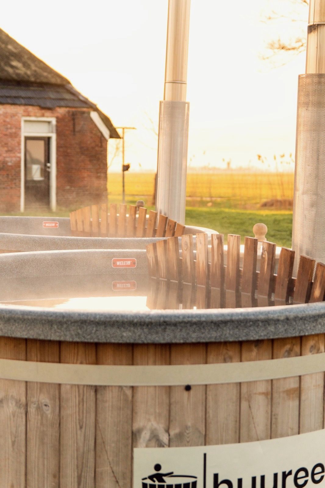 Een houten hottub met water er in en damp erboven. 