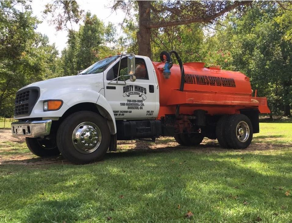 A white and orange truck is parked in a grassy field