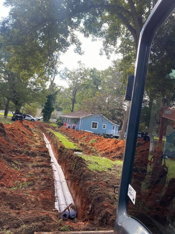 A blue house is being built in the middle of a dirt field.