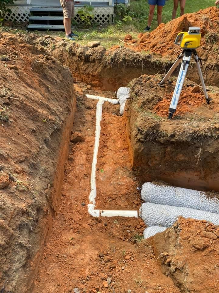A man is standing in the dirt next to a tripod.