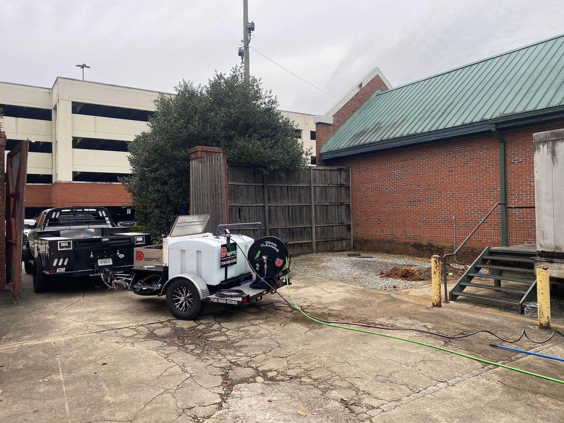 A trailer with a motorcycle attached to it is parked in front of a brick building.