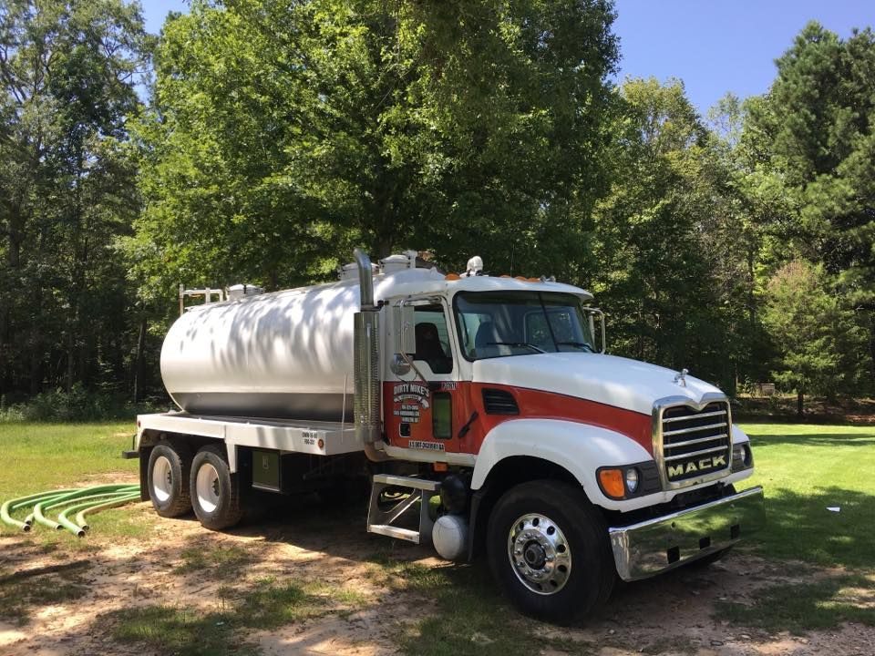 A white and red mack truck is parked in a grassy field.