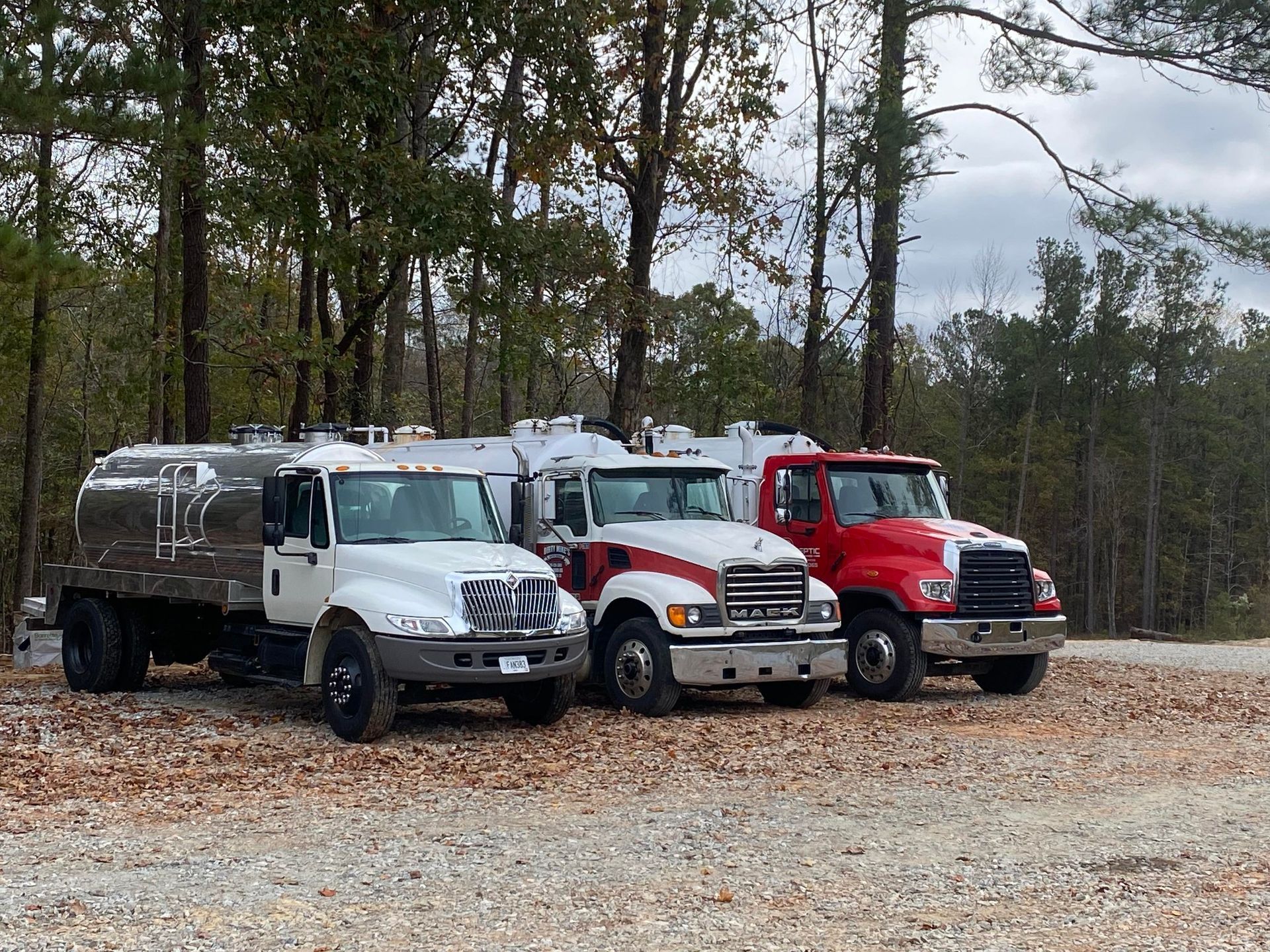 Three trucks are parked next to each other in a gravel lot.
