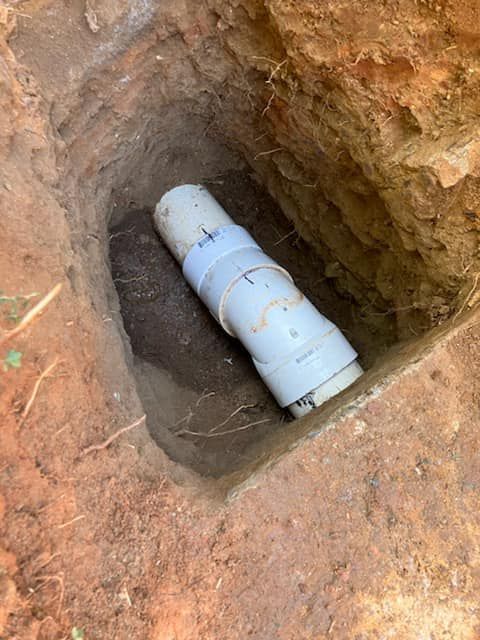 A white pipe is sitting in a hole in the ground.