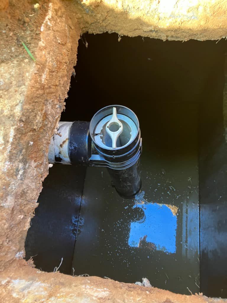 A black pipe is sitting in the middle of a hole in the ground.