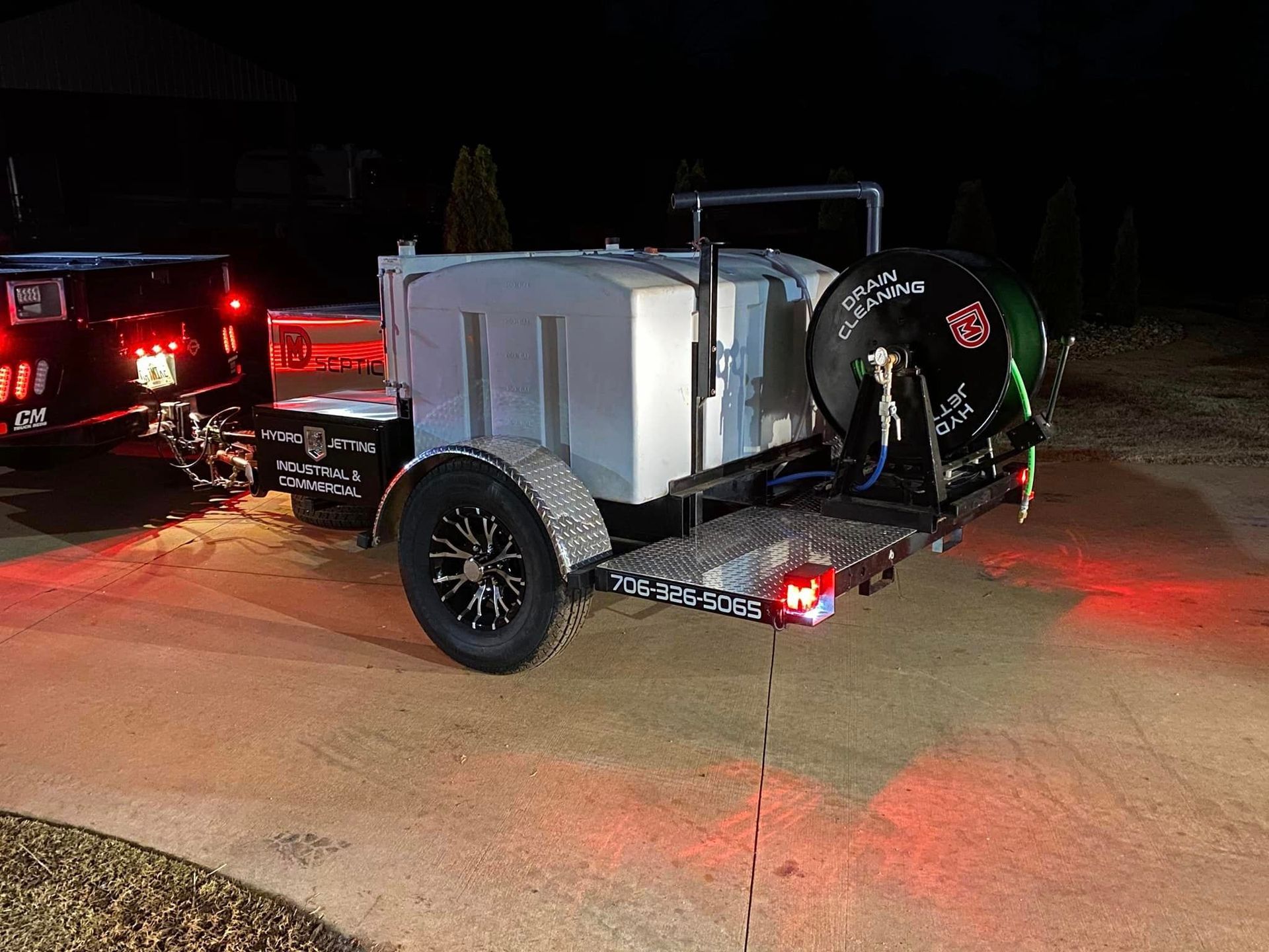 A trailer with a hose attached to it is parked in a driveway at night.