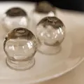 Small clear glass spheres arranged on a white plate, with one in the foreground.