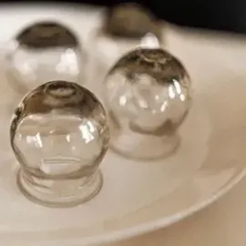 Four clear glass domes with dark tops arranged on a white plate