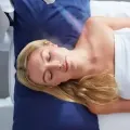 Woman sleeping on a blue pillow under a white blanket