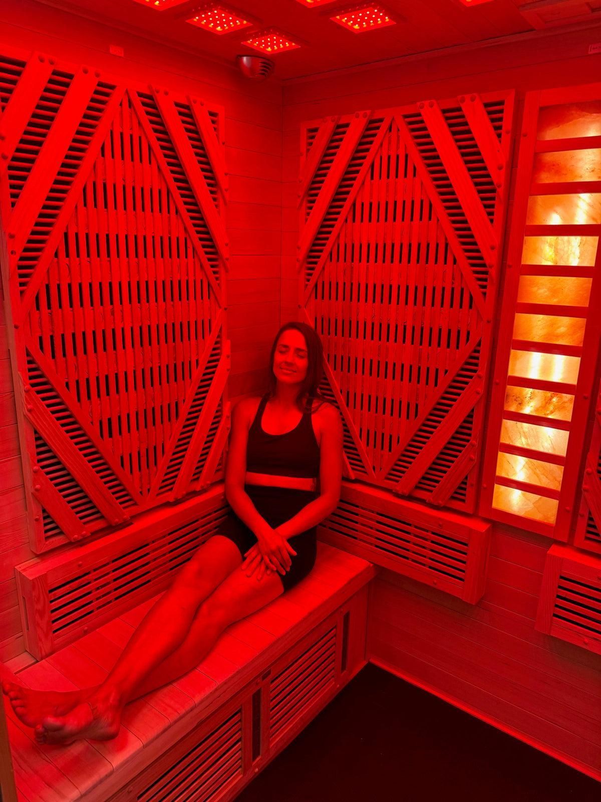 Person seated in a red-lit geometric room, smiling at the camera.
