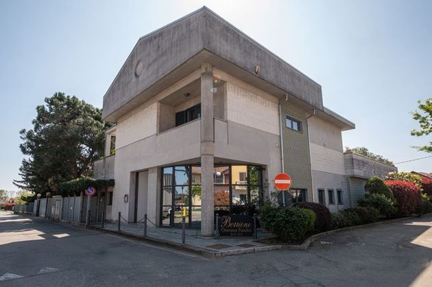 Negozio d'angolo con ampie vetrine e segnale di stop accanto a un parcheggio.