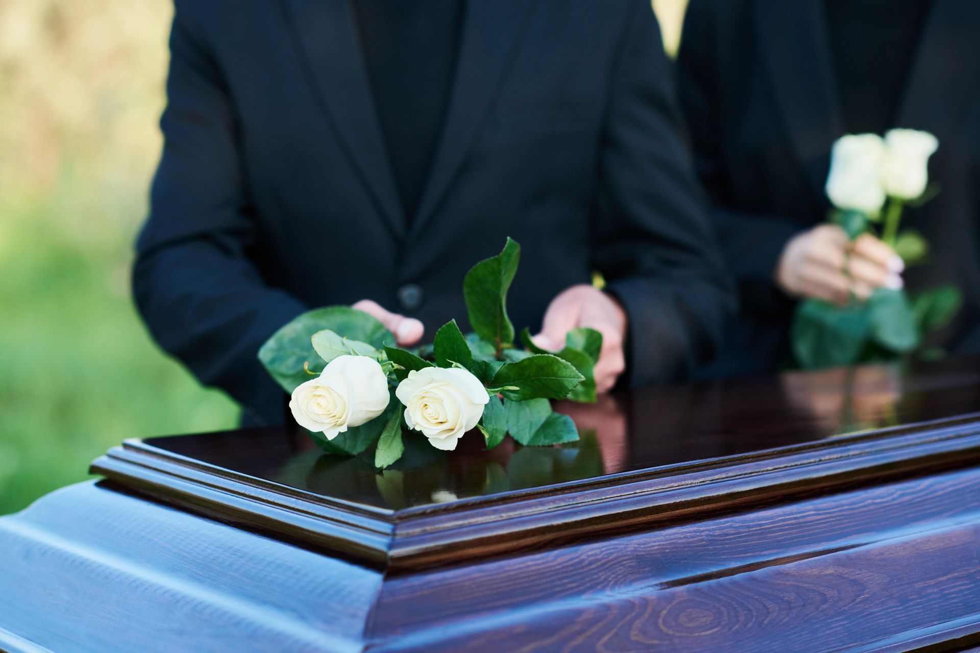 Bara nera con composizione floreale bianca a un funerale.