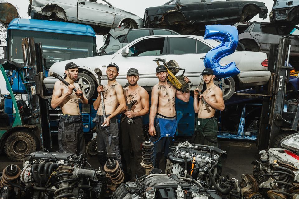 Grupelė vyrų prieš krūvą automobilių detalių