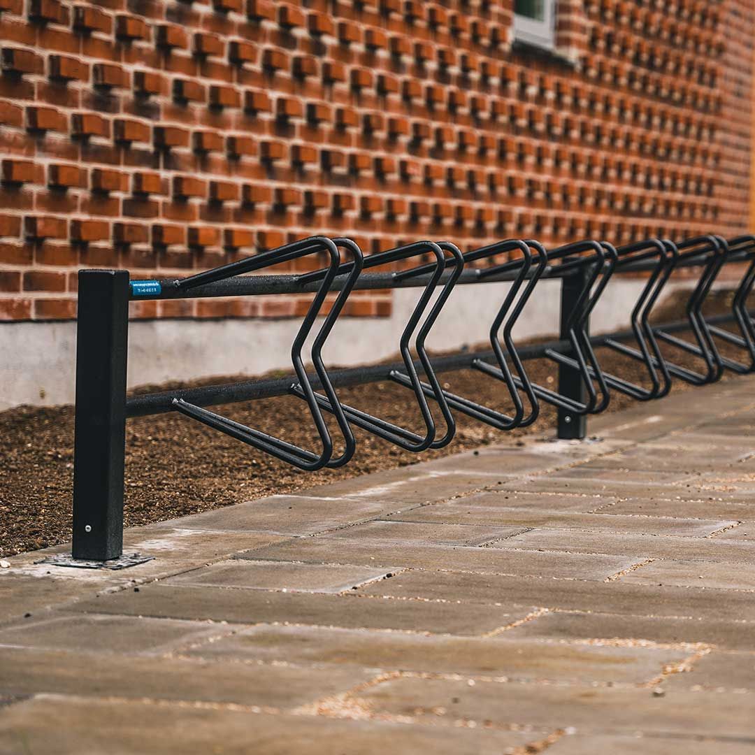 En række af cykelstativer foran en murstensbygning.