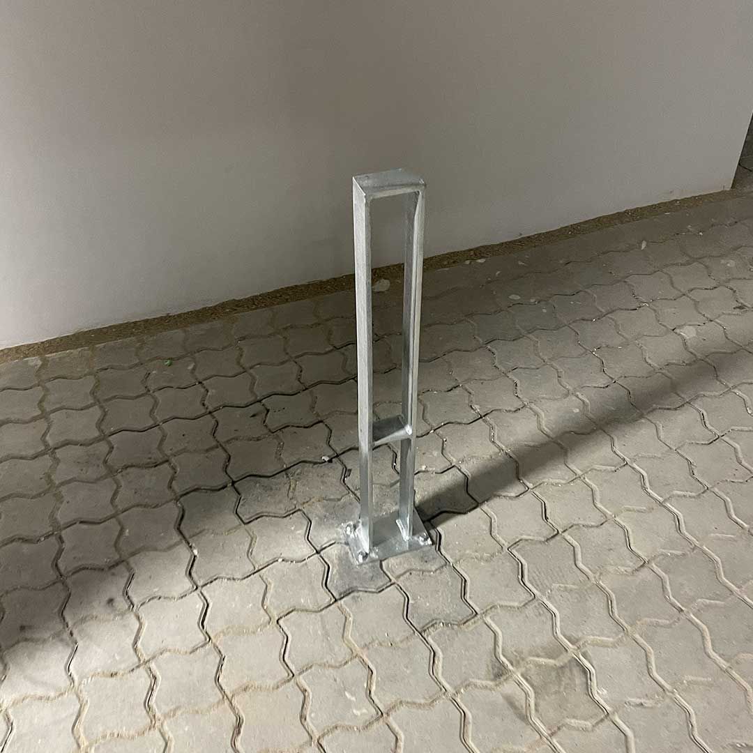 En pullert på et murstensgulv nær en hvid væg.