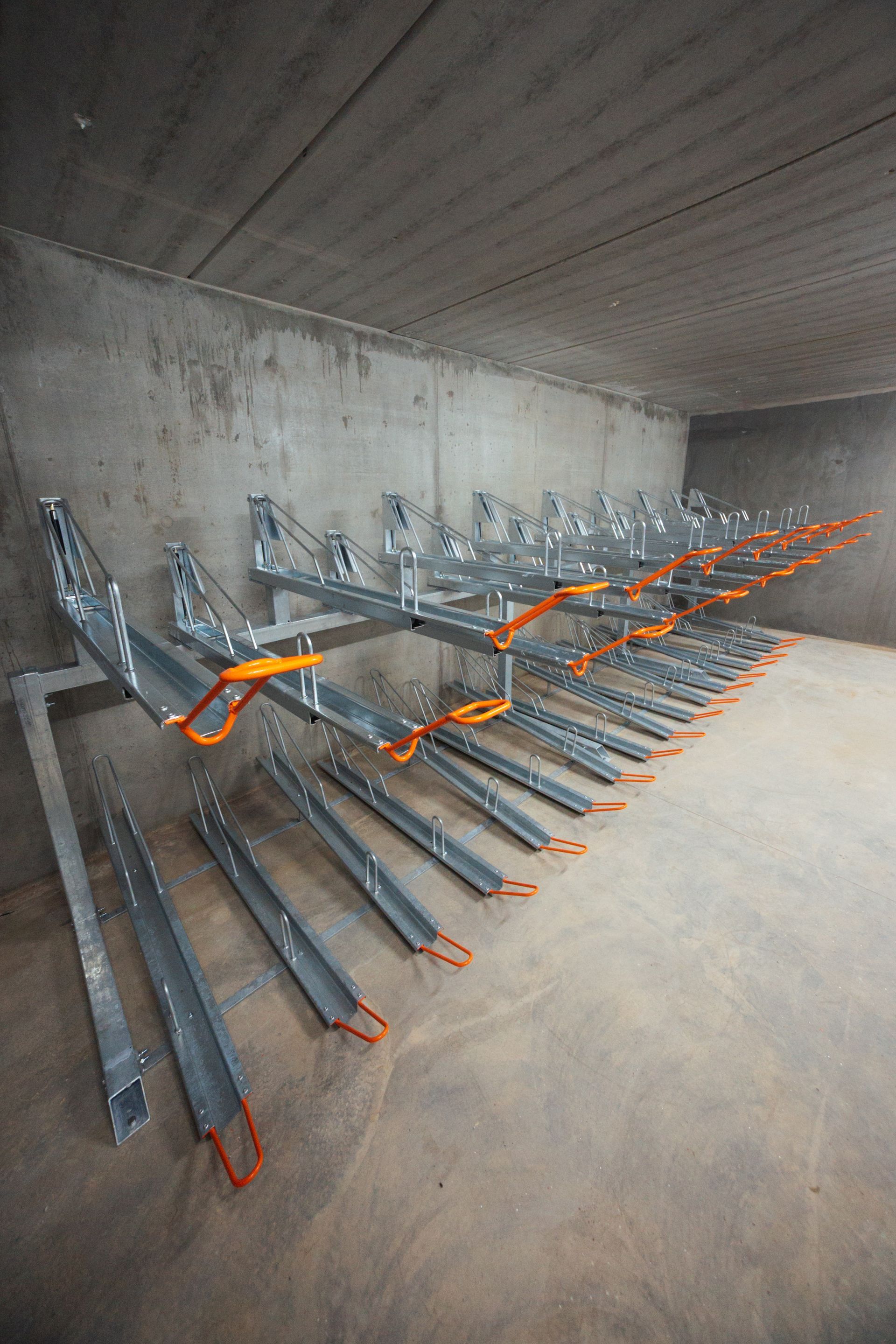 Metalcykelstativer med gasdæmper monteret på en betonvæg.