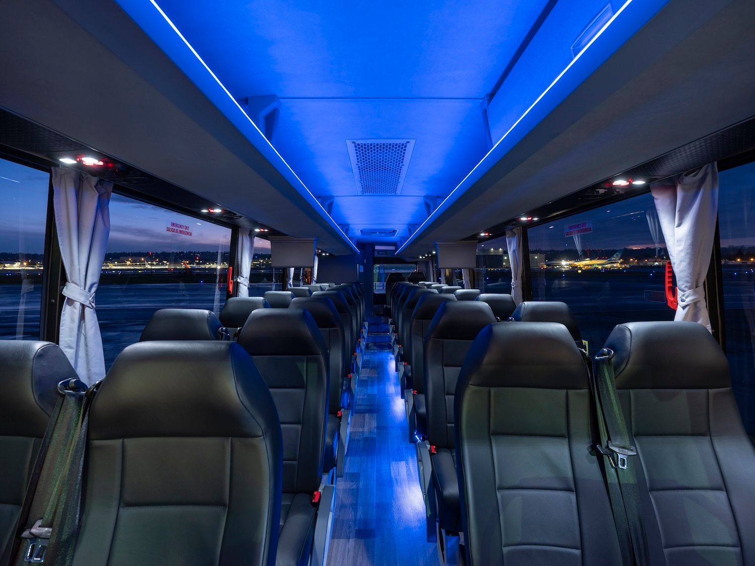 Empty bus interior with blue LED lighting and rows of black seats