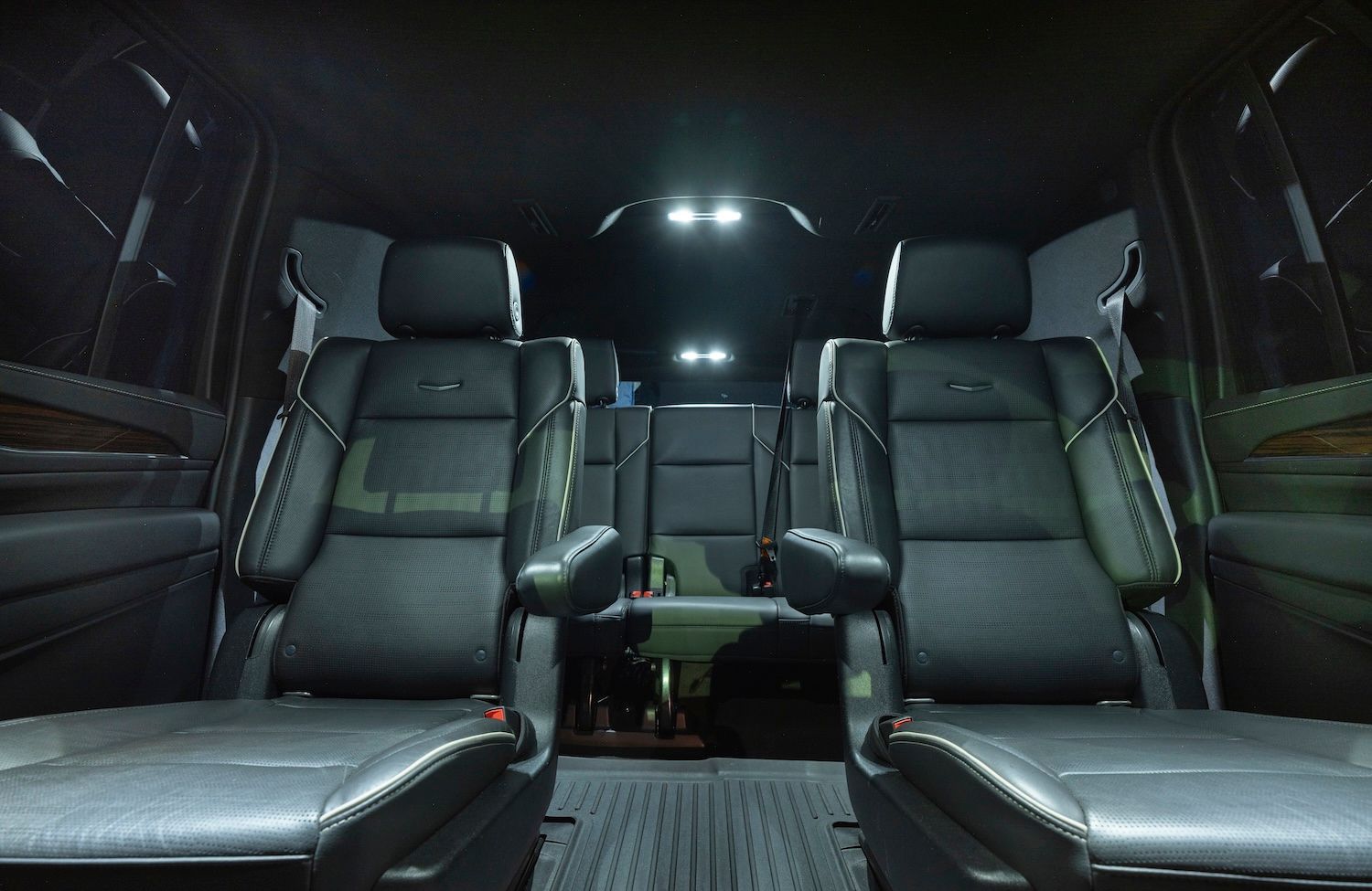 Empty black van interior with four leather seats and overhead lights