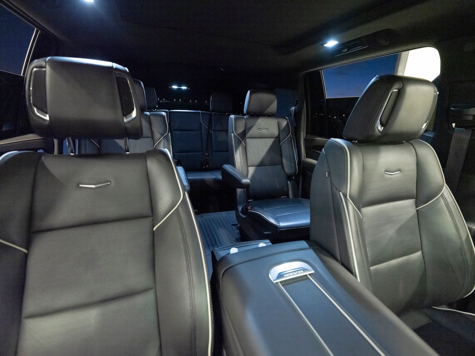 The interior of a vehicle featuring black leather bucket seats and a central console, viewed from the second row.