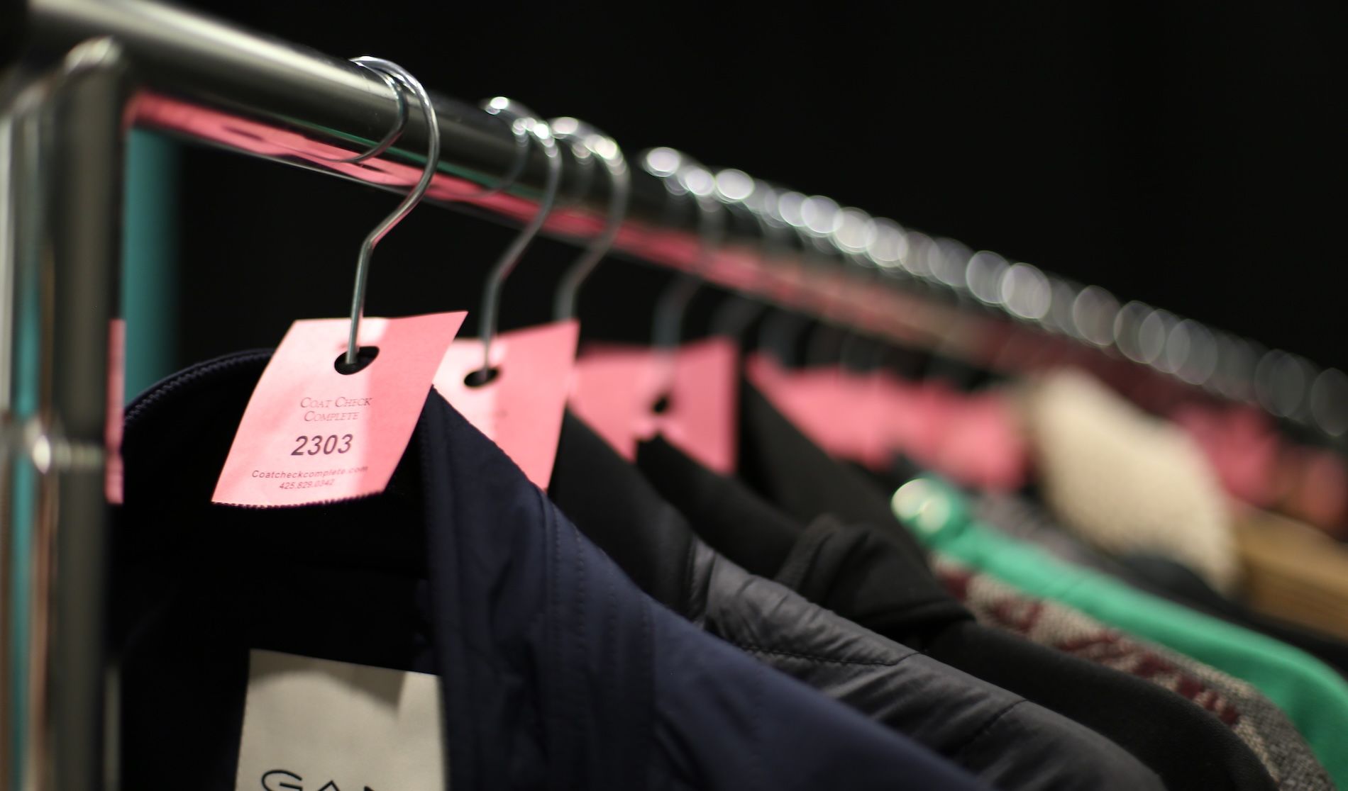 Clothing items hanging on a rack, each marked with a small, rectangular pink tag.