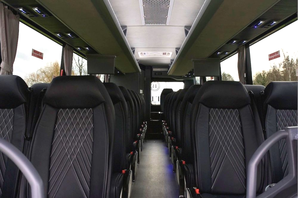 Empty bus interior with black seats and green overhead panels