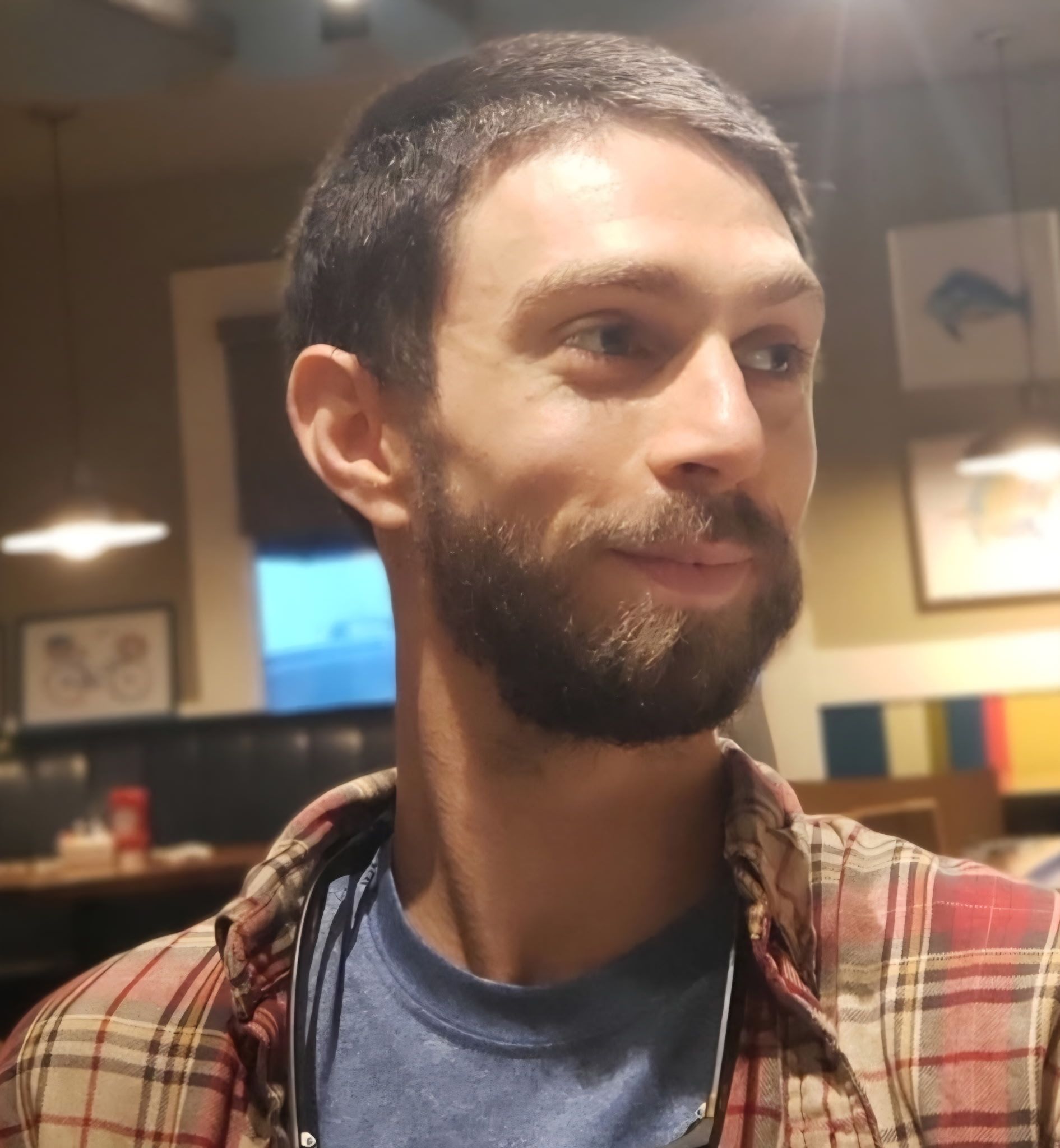 Coach in gym smiling, holding clipboard and stopwatch.