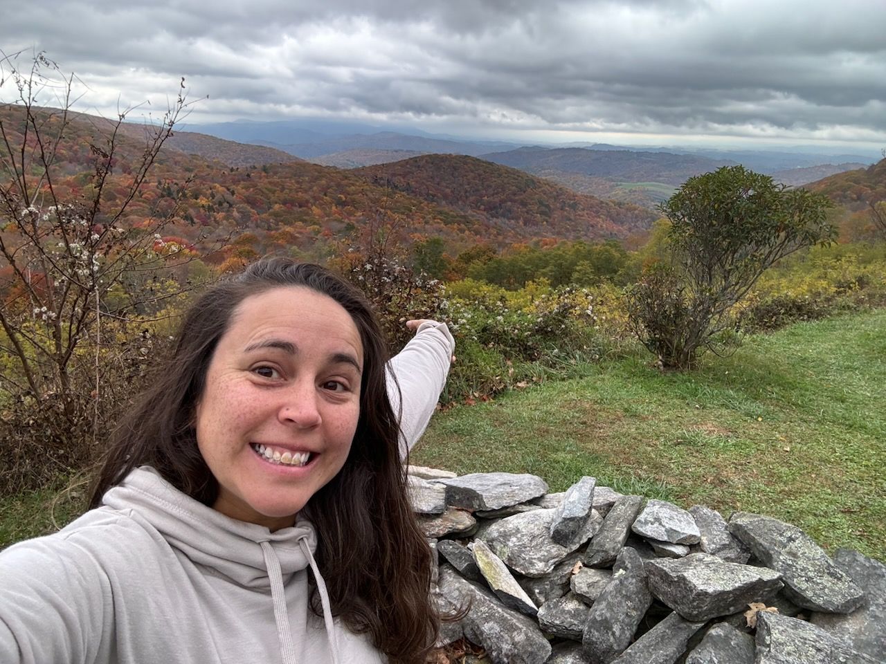 Woman smiling with arms crossed, wearing purple jacket and whistle on a field.