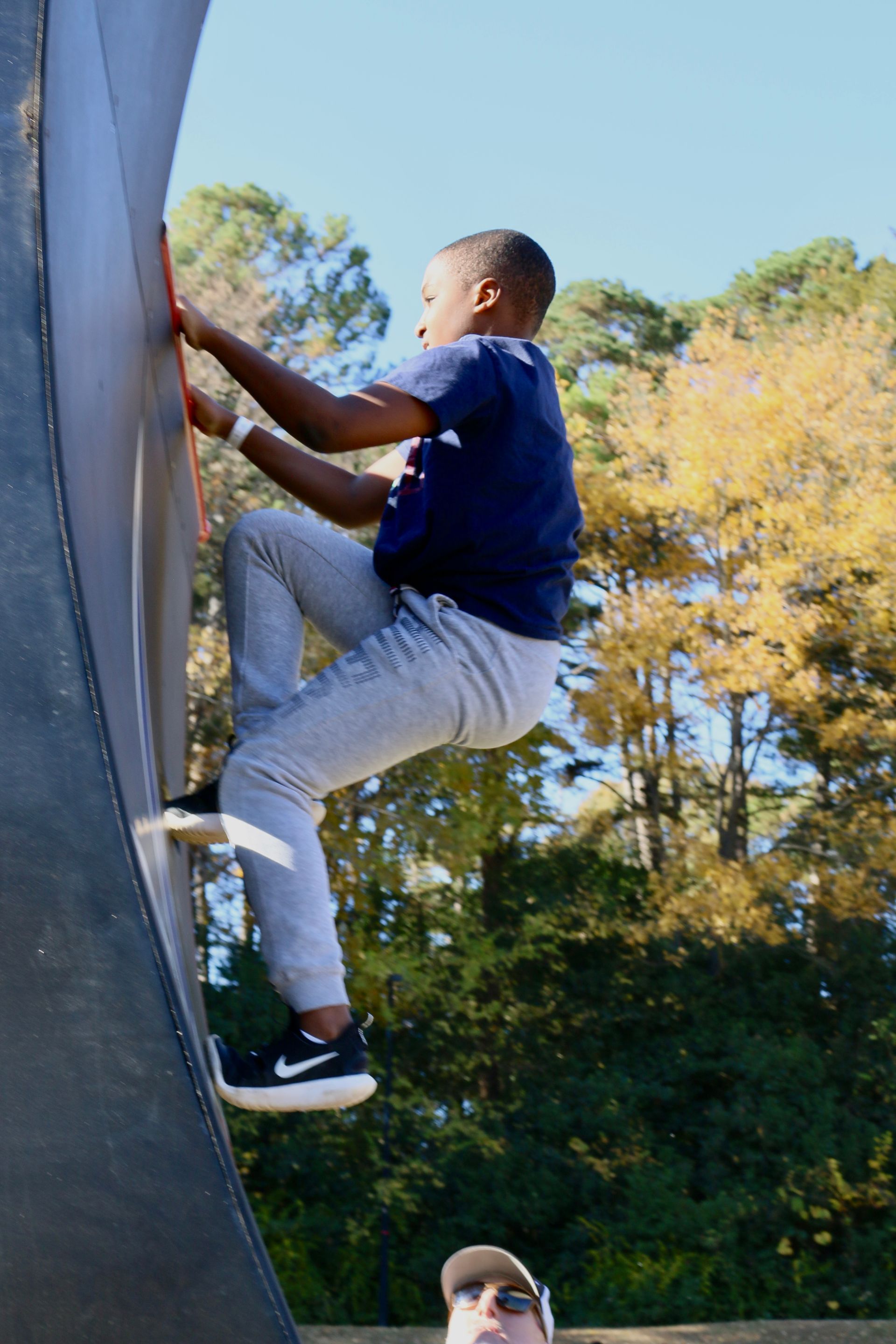 People on an obstacle course. Two people use poles to swing between platforms at an outdoor event.