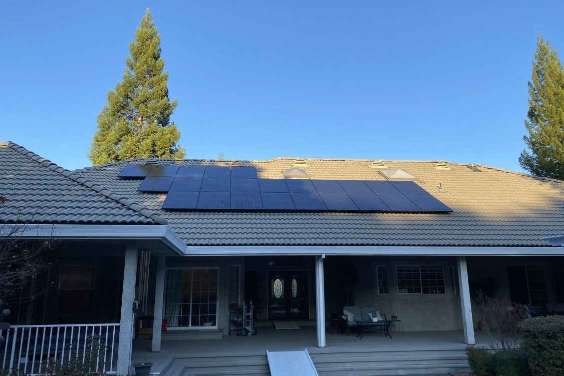 A house with solar panels on the roof and a porch.